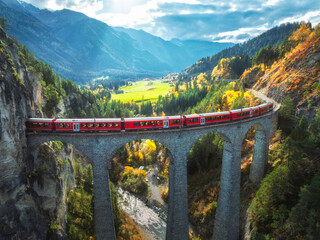 Aerial view of red train on Landwasser viaduct in autumn in Alps