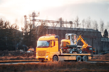 Yellow truck with excavator on flatbed trailer
