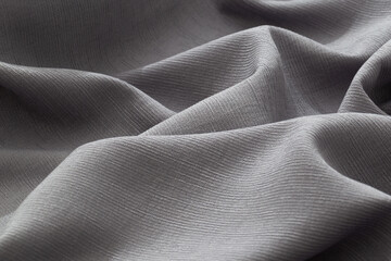 Soft grey fabric draped with flowing folds and textured surface
