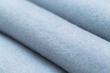 Close-up macro shot of soft, light blue felt fabric rolls, showcasing its delicate texture and...