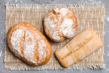 Assortment of freshly baked bread with napkin on rustic table top view. Healthy unleavened bread. French bread