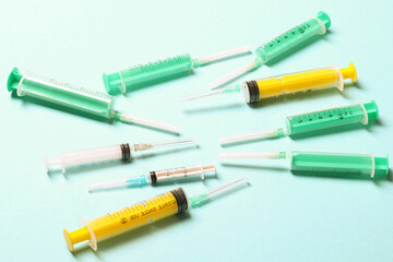 Fototapeta premium Top view of medical syringes with needles at blue background with copy space. Injection treatment concept