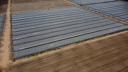 Open farmland with irrigation system irrigating the light brown soil