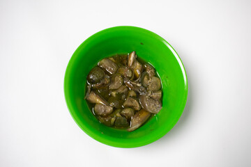 A green plastic bowl contains green eggplant vegetable dishes. The background is white.
