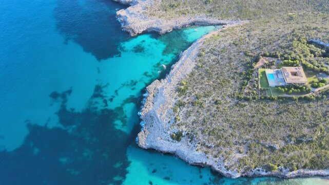 Experience the breathtaking views of Cala Varques, located near Porto Cristo in Majorca. The vibrant blue waters contrast beautifully with the rugged coastline and lush greenery.
