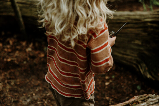 Child holding a pocket knife building a forest cabin