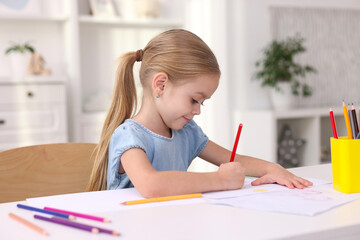 Cute girl drawing at white table in kindergarten