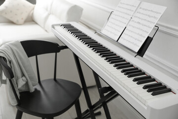 Synthesizer with music sheets and chair at home, closeup