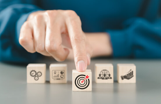 Business growth concept. Setting business objective target goal, Person points at wooden block with red dartboard icon business goals. teamwork, data analysis, growth, processes, strategic planning,