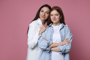 Family portrait of beautiful mother with teenage daughter on pink background