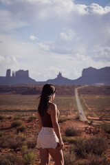 Unrecognizable young woman sightseeing on the road against the backdrop of Monument Valley, on the west coast of the United States.