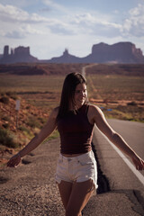 Attractive young woman sightseeing on the road against the backdrop of Monument Valley, on the west coast of the United States.