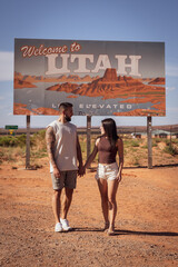 Young couple in love on a road trip along the Utah sign on the West Coast of the United States.