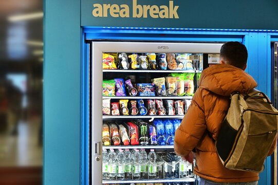 Male backview standing in front of food and drink vending machine at subway station Turin Italy February 1 2025