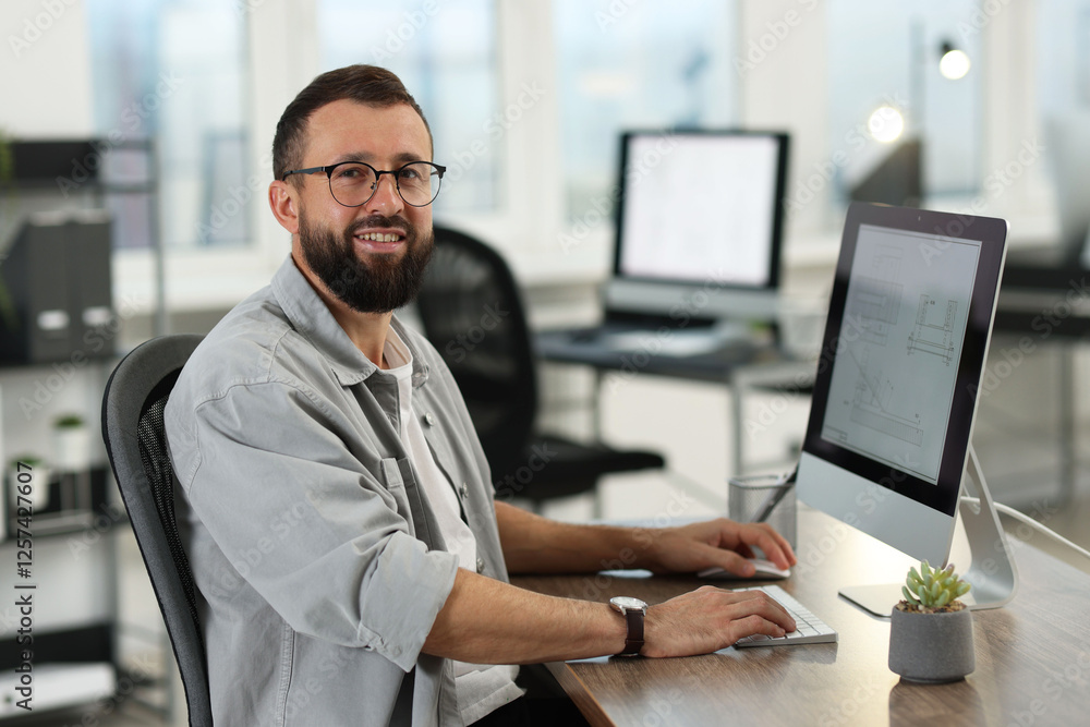 Poster technician making digital engineering drawing on computer at desk in office