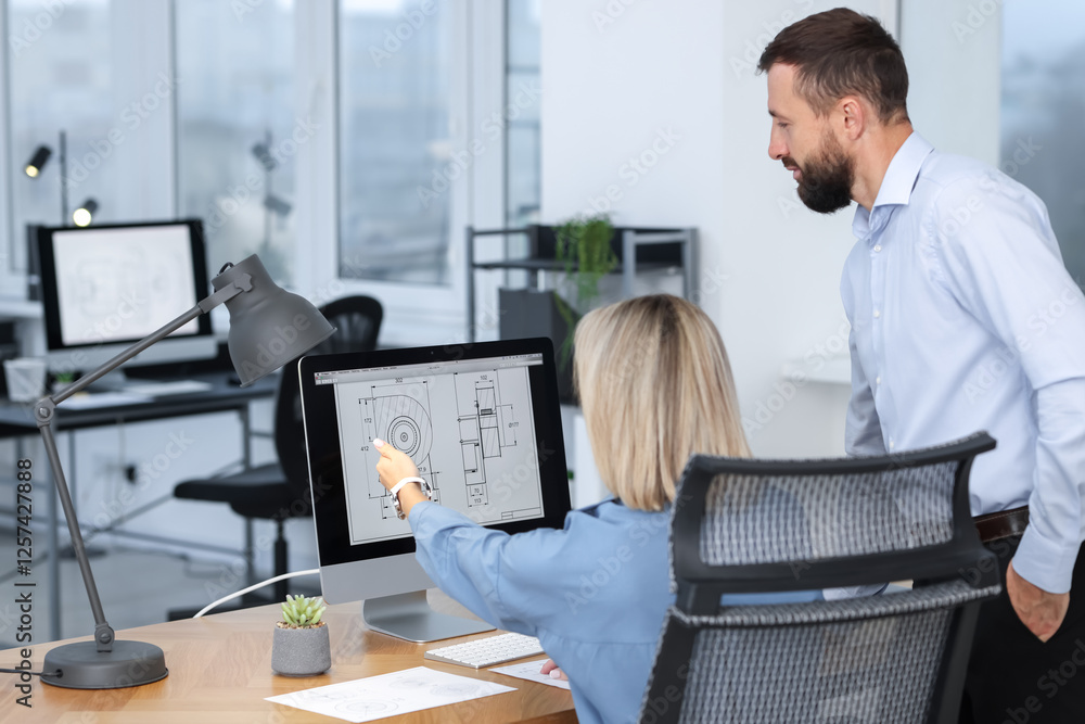 Poster technicians making digital engineering drawing on computer at desk in office