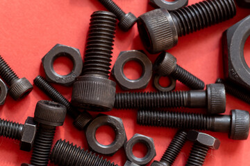 赤背景に並ぶ複数の六角ナットとボルト