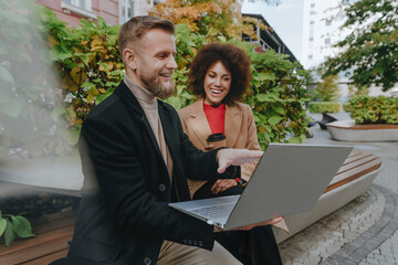 Smiling businessman using laptop with colleague at office park