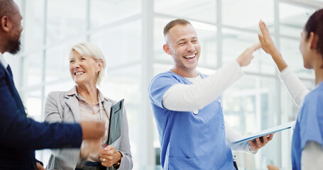 Obraz premium Doctors, high five and celebration with group at hospital for breakthrough, progress and medical solution. People, men and women with cheers, success and goals for healthcare innovation at clinic