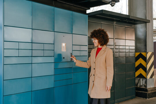 Businesswoman scanning locker with smart phone at parking lot