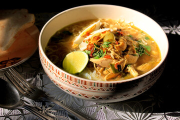 a bowl of Javanese chicken soto with lime wedges