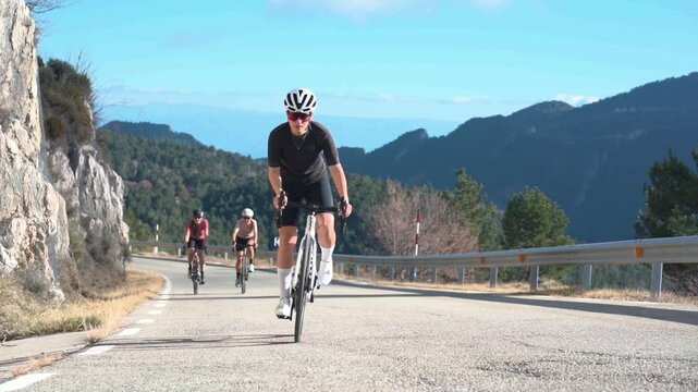 Female cyclist leading a group on a winding mountain road during a climb