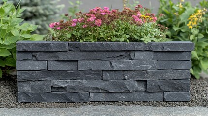 Dark gray stone retaining wall in garden with flowers