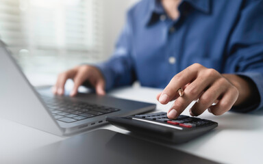 Close up businessman hand using calculator to budgeting and tax calculation monthly expenses. budget management and accounting on table. Business finance accounting banking concept.