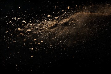 A dynamic image displays a scattered cloud of tan-colored dust and small particles suspended in mid-air against a stark, solid black background.