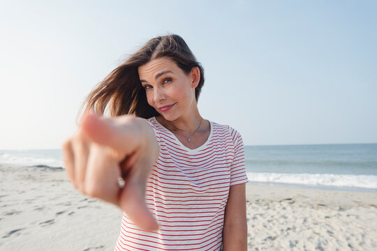 Beautiful woman pointing at camera on beach
