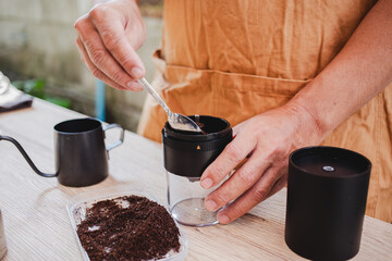  barista scooping freshly ground coffee into portable grinder, preparing for homemade brew. aroma...