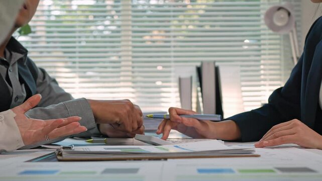 Business colleagues are discussing and planning work in a meeting, analyzing financial data and using a calculator to evaluate project feasibility