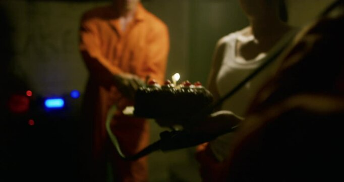 People in basement about to fling cake with lite candle on a homemade slingshot, closeup