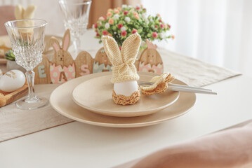 Festive Easter table setting with Easter bunny made from egg and knitted ears. Easter celebration concept