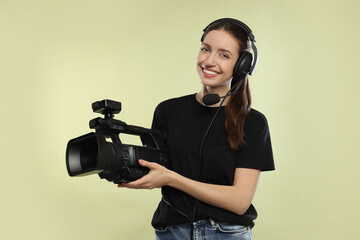 Happy woman with professional video camera on pale olive background