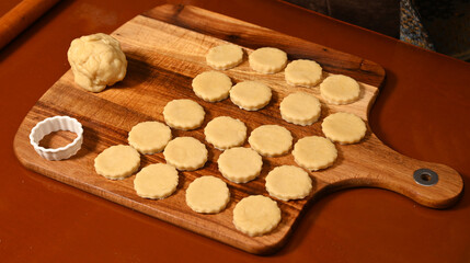 Baking process with freshly rolled cookie dough shapes on a wooden surface in a cozy kitchen setting