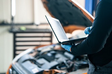 Serviceman with laptop checks car software in car service
