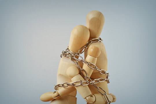 Two wooden mannequins bound by chains - Concept of toxic relationship and emotional dependence