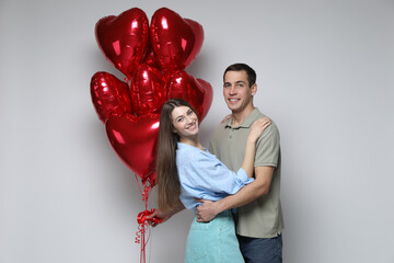 Lovely couple with heart shaped balloons on light background. Valentine's day celebration