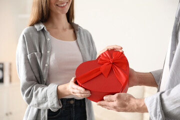 Lovely couple with gift box indoors, closeup. Valentine's day celebration