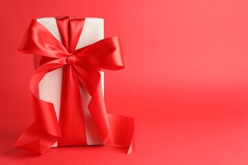 Gift box with beautiful bow on red background, space for text