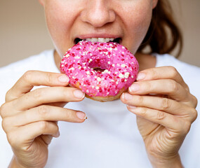 Close-up of a woman eating a donut with pink glaze.