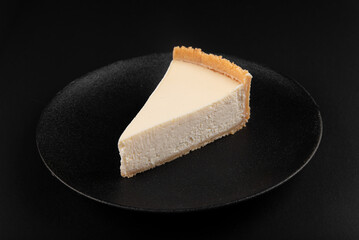 New York cheesecake on a dark plate on a black background
