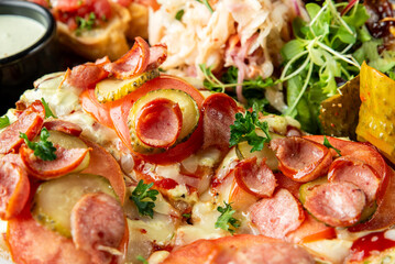 Delicious close-up of a savory pizza topped with sliced tomatoes, pickles, pepperoni, and fresh herbs. Accompanied by colorful salad and dipping sauce for a tasty meal. Perfect for food lovers!