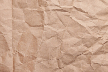 Wrinkled recycled kraft paper surface with creases and fold. Eco-friendly textured crumpled brown background for packaging. Close-up