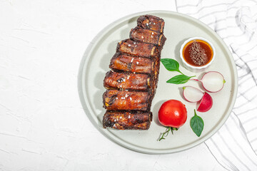 Baked pork ribs with spices, vegetables and sauce. Traditional ingredient for BBQ, picnic concept