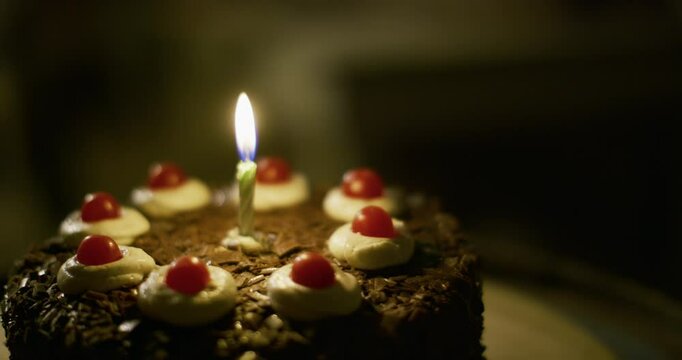 Close up on delicious looking chocolate cake with single lite candle in middle, steady cam movement