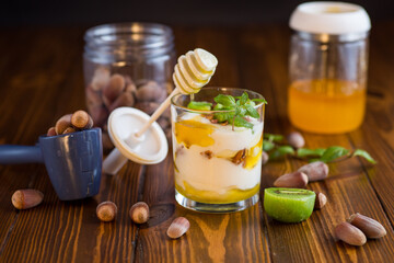 homemade yogurt with kiwi, honey and nuts in a glass on a wooden table