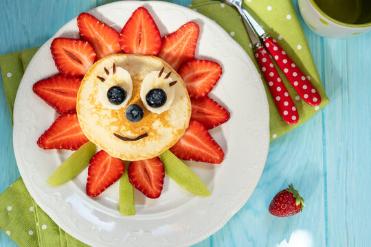 Naklejki A plate of pancakes with a smiling face made of strawberries and bananas