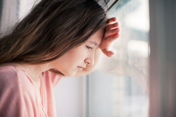 Thoughtful girl looking at window, sad depressed teenager spending time alone at home